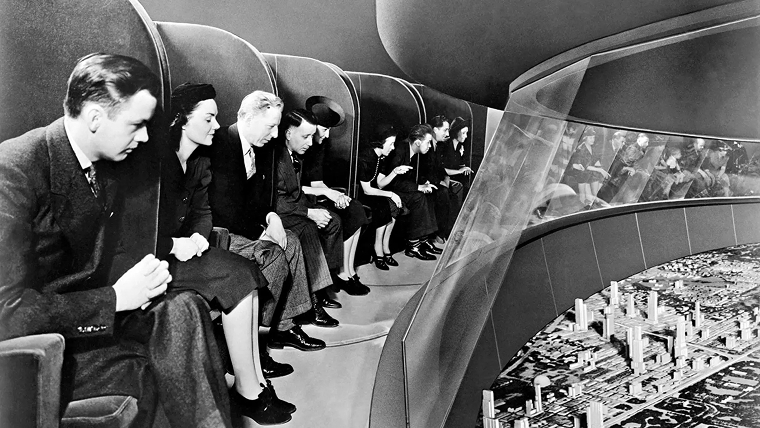 Visitors at GM’s Futurama exhibit at the 1939 World’s Fair viewing a model of a futuristic American city from moving seats.